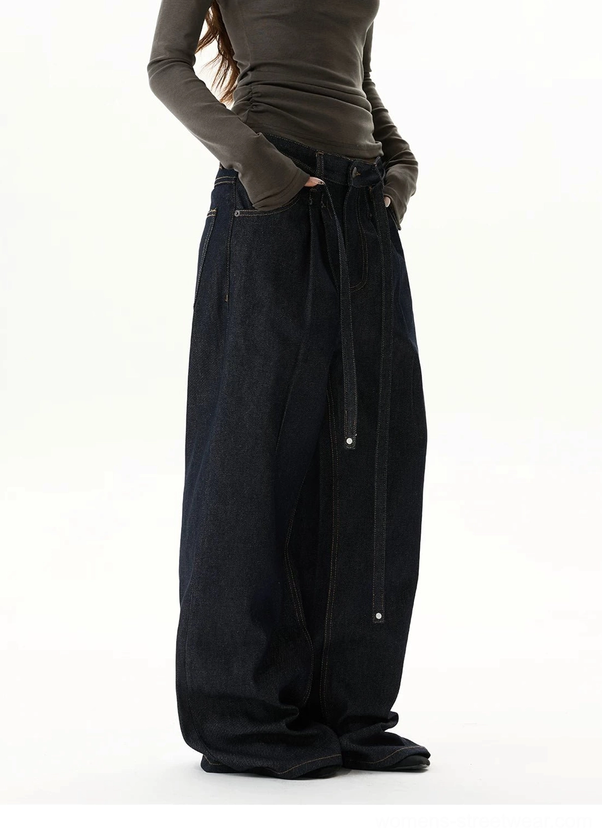 Wide-leg indigo denim jeans with front pleats, adjustable waist tie, vintage wash finish, and dramatic puddling silhouette