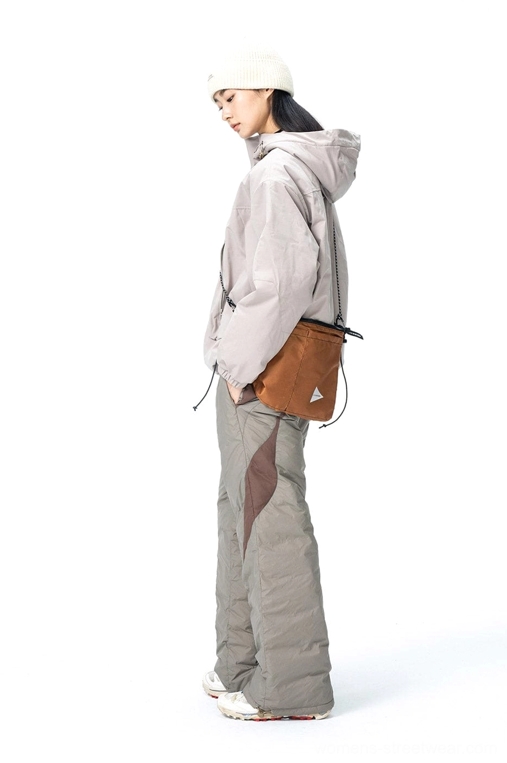 Side view of wide-leg padded track pants styled with a matching hooded jacket and neutral outdoor accessories