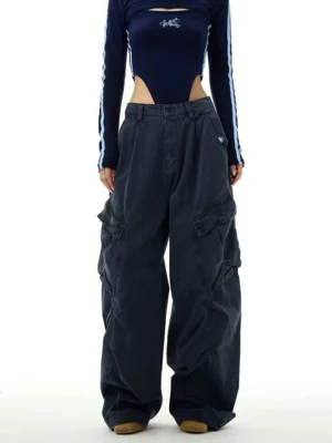 Wide-leg streetwear cargo workwear pants styled on a female model with a cropped top, showing the relaxed high-waisted silhouette, front pleats, and oversized utility pockets