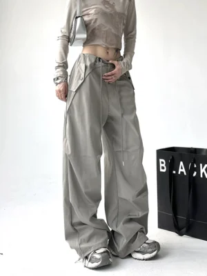 Light gray wide-leg utility cargo pants shown from the front with drawstring waist, oversized flap pockets, relaxed streetwear fit, and long floor-skimming silhouette