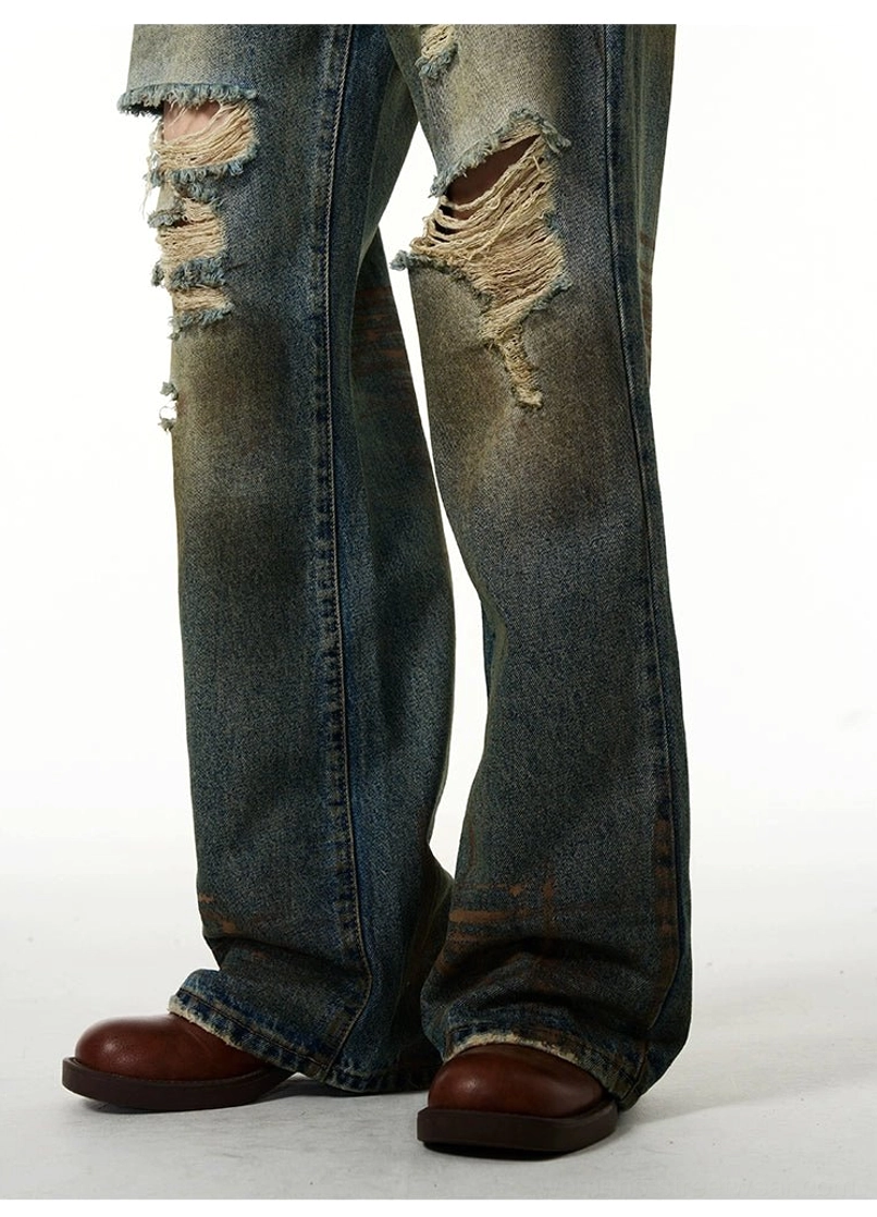 Close-up of wide-leg vintage washed blue jeans with heavy ripped knee details and brown shoes in a streetwear outfit