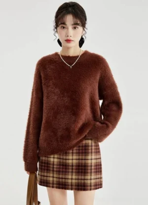 Wine red fuzzy crew neck sweater shown from the front with a relaxed drop shoulder fit and brown plaid mini skirt