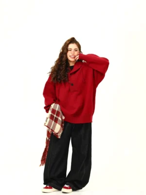 Wine red oversized knit hoodie sweater shown from a three-quarter angle with black wide-leg pants and red sneakers