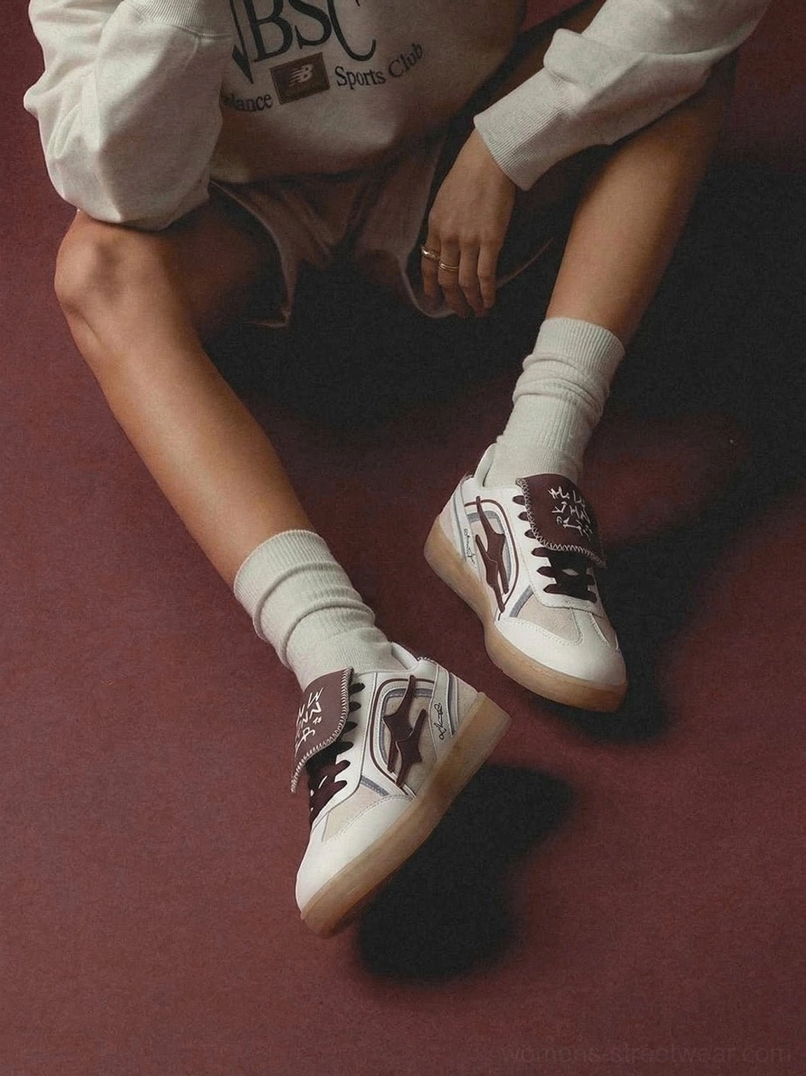 Model wearing white and wine red retro strap sneakers with beige crew socks in a relaxed streetwear outfit