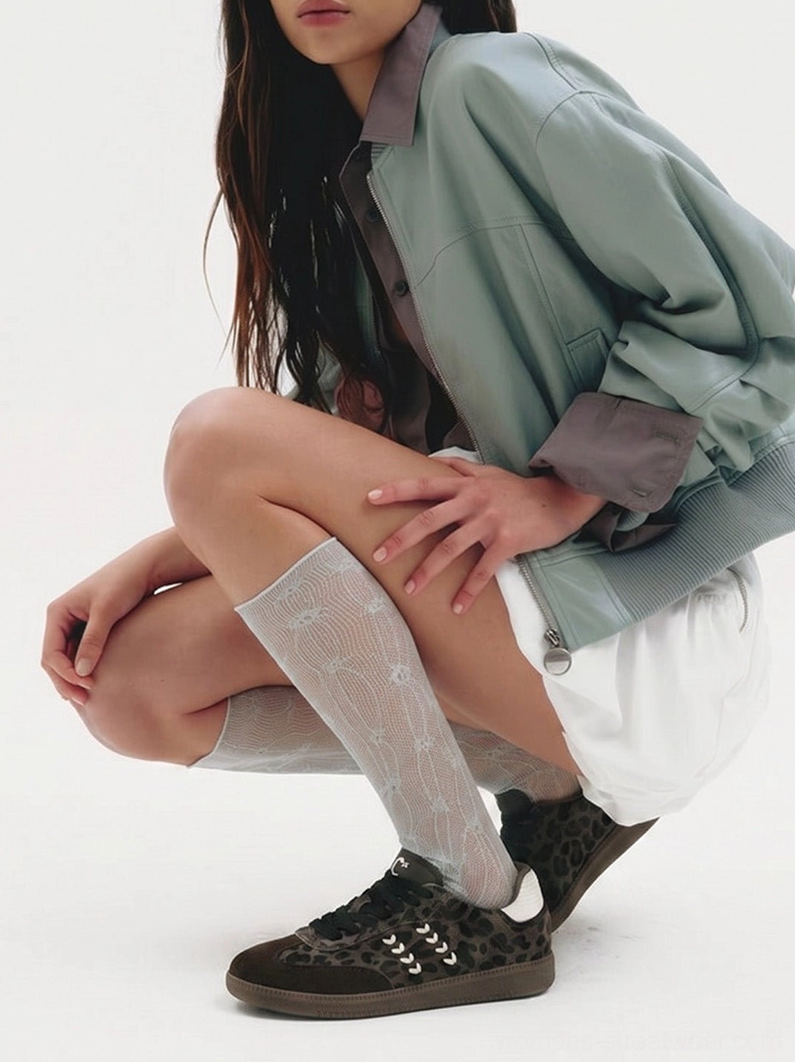 Women wearing forest leopard print low top sneakers with a mint green cropped jacket, white shorts, and patterned sheer socks in a streetwear outfit