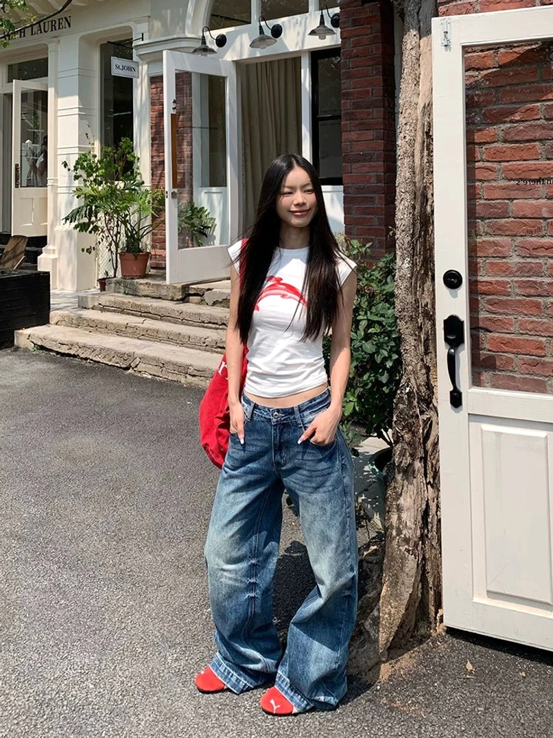 Front view of women sun-faded wide-leg denim jeans styled with red accessories outside a brick doorway