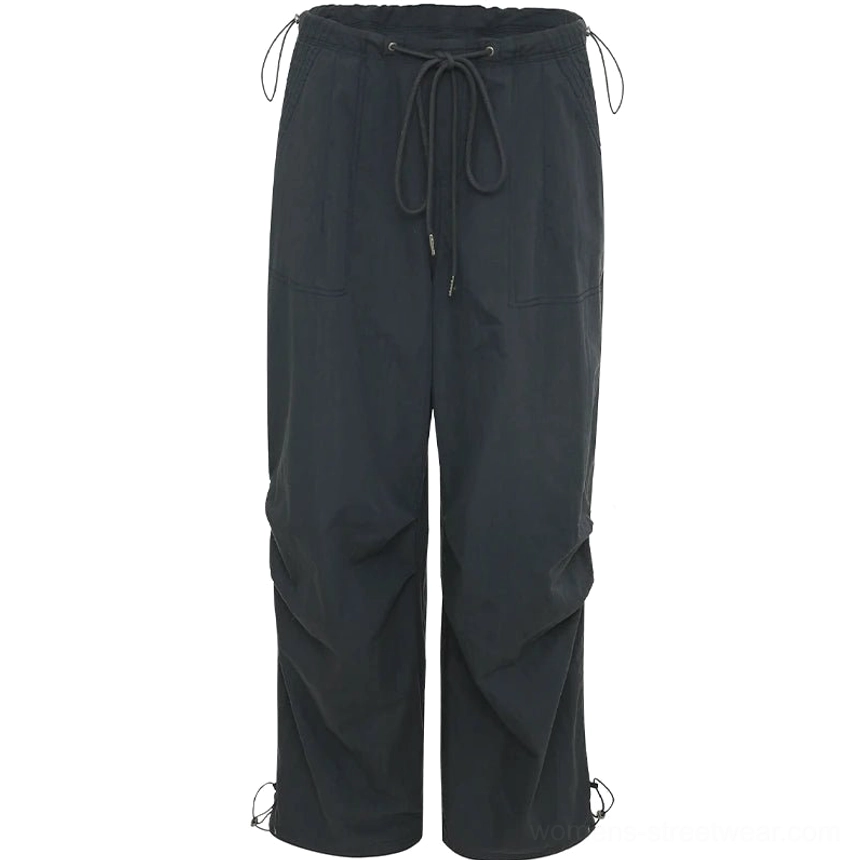 Black women's wide-leg parachute cargo pants with adjustable drawstring waist, gathered ankle hems, and utility-inspired seam details