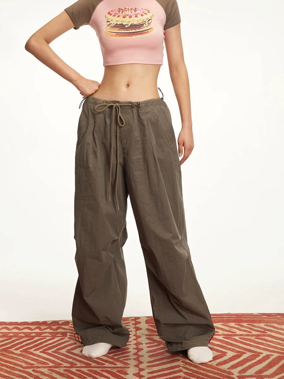Three-quarter view of dark brown women's parachute cargo pants featuring a loose wide-leg fit and adjustable ankle drawstrings