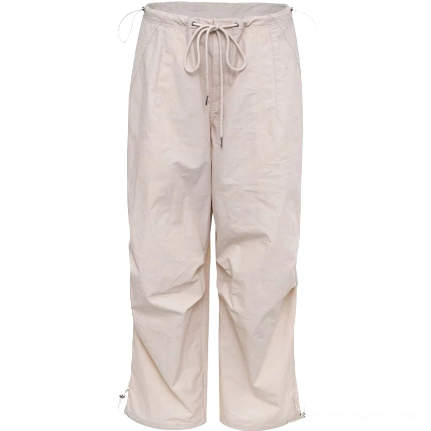 Light beige women's relaxed parachute cargo pants flat lay with lightweight wrinkled texture, wide legs, and adjustable hems
