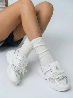 Women's air-mesh streetwear sneakers styled with cream ribbed socks and dark denim shorts in a relaxed casual outfit