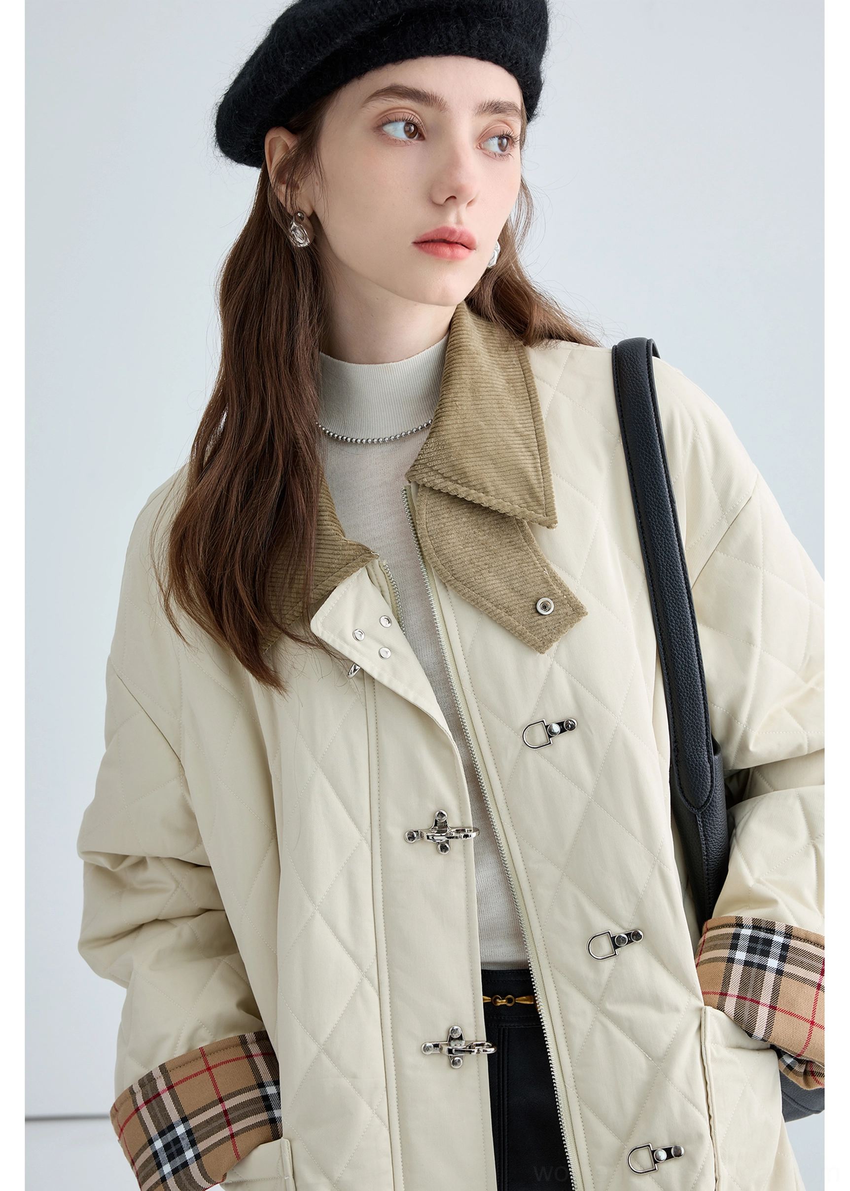 Metal buckle fastener close-up on women's beige quilted cotton jacket with contemporary utility-inspired hardware