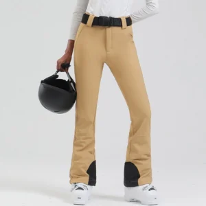 Women's khaki belted flared ski pants styled with white ski boots and helmet for mountain streetwear
