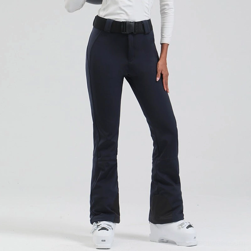 Women's navy blue belted flared snow pants with slim fit silhouette and black ski boot cuffs