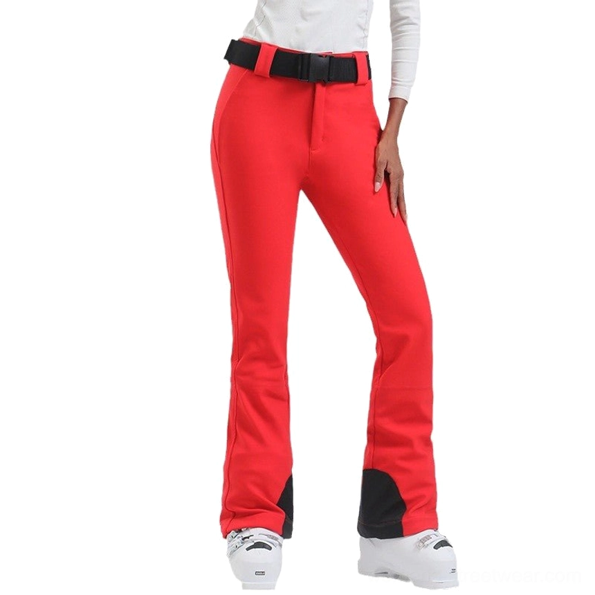 Women's red flared ski pants with wide black waist belt and waterproof stretch snow-ready design