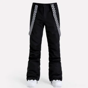 Front view of women's black checkerboard snow pants with detachable suspenders, flared ski streetwear legs, black ankle patches, and white snow shoes