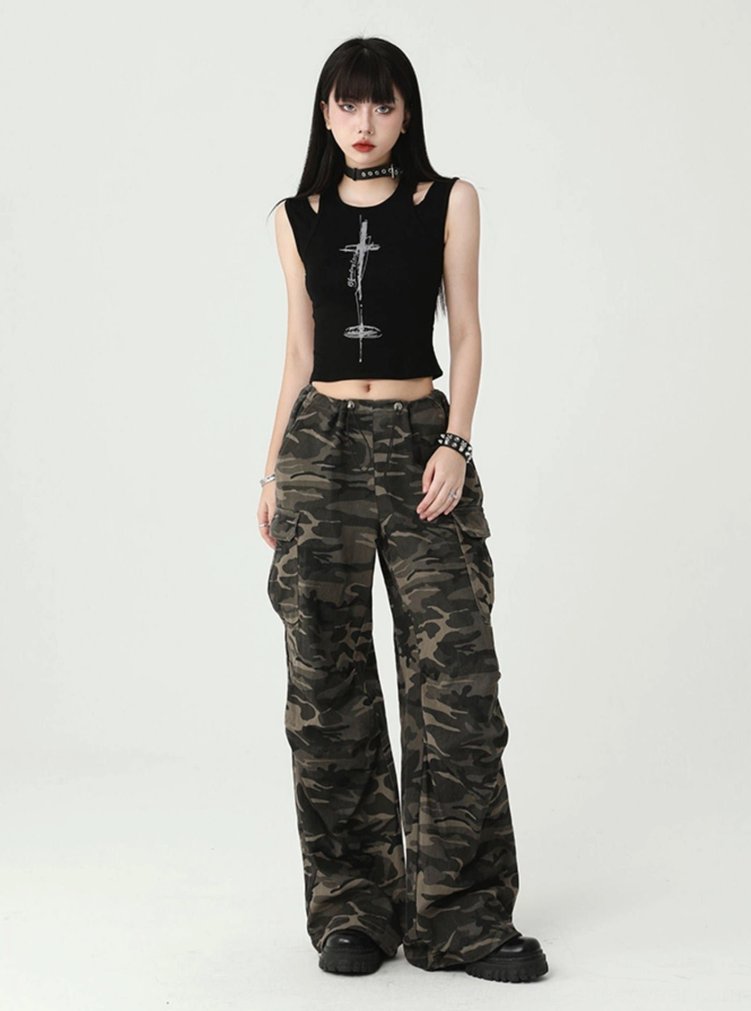 Front view of a women's black cutout cross print tank top with cropped hem, ribbed fabric, silver graphic, and punk jewelry styling