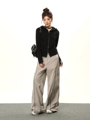 Full-body styling view of a women's black fitted zip-up hoodie worn with light gray cargo pants and a chain crossbody bag