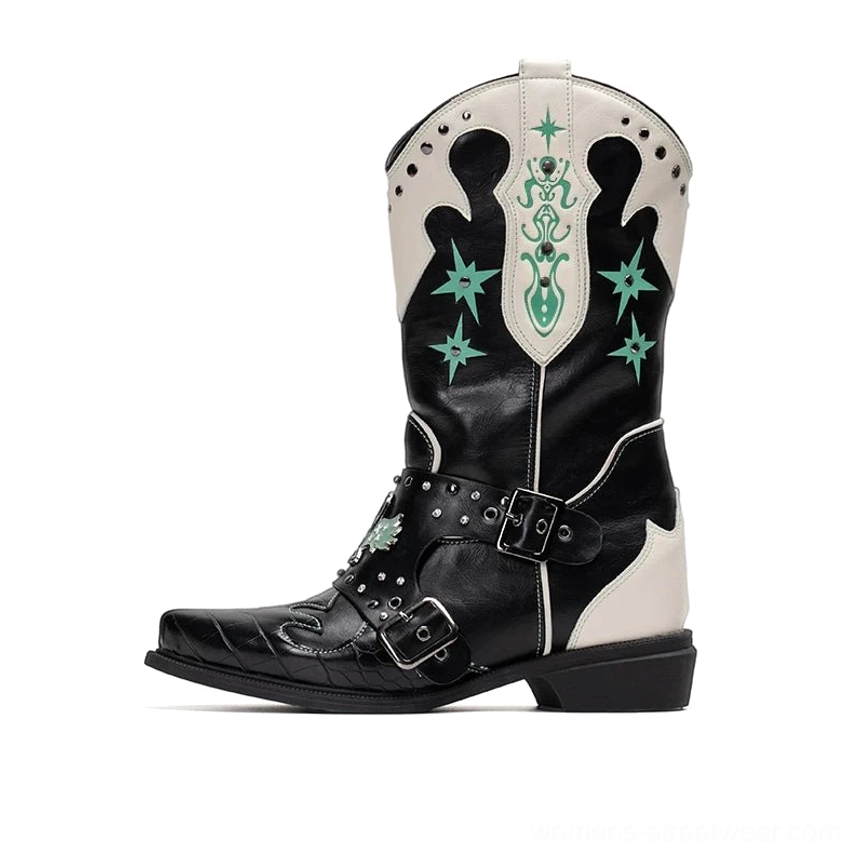 Full side profile of women's black and ivory cowboy boots with green western star embroidery, adjustable metal harness straps, pointed toes, and rubber soles