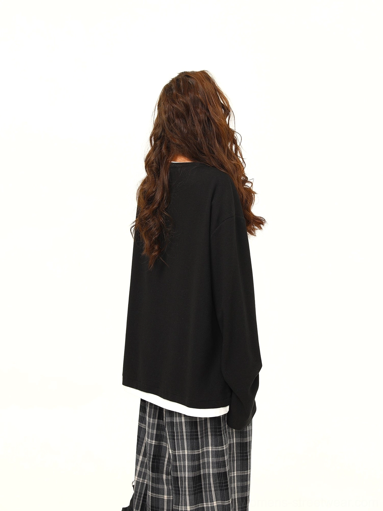 Back view of black layered hem waffle knit oversized Henley pullover with visible white contrast shirt trim