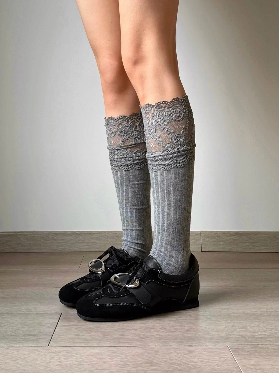 Close view of black leather German trainer sneakers with grey lace socks and metallic buckle detail