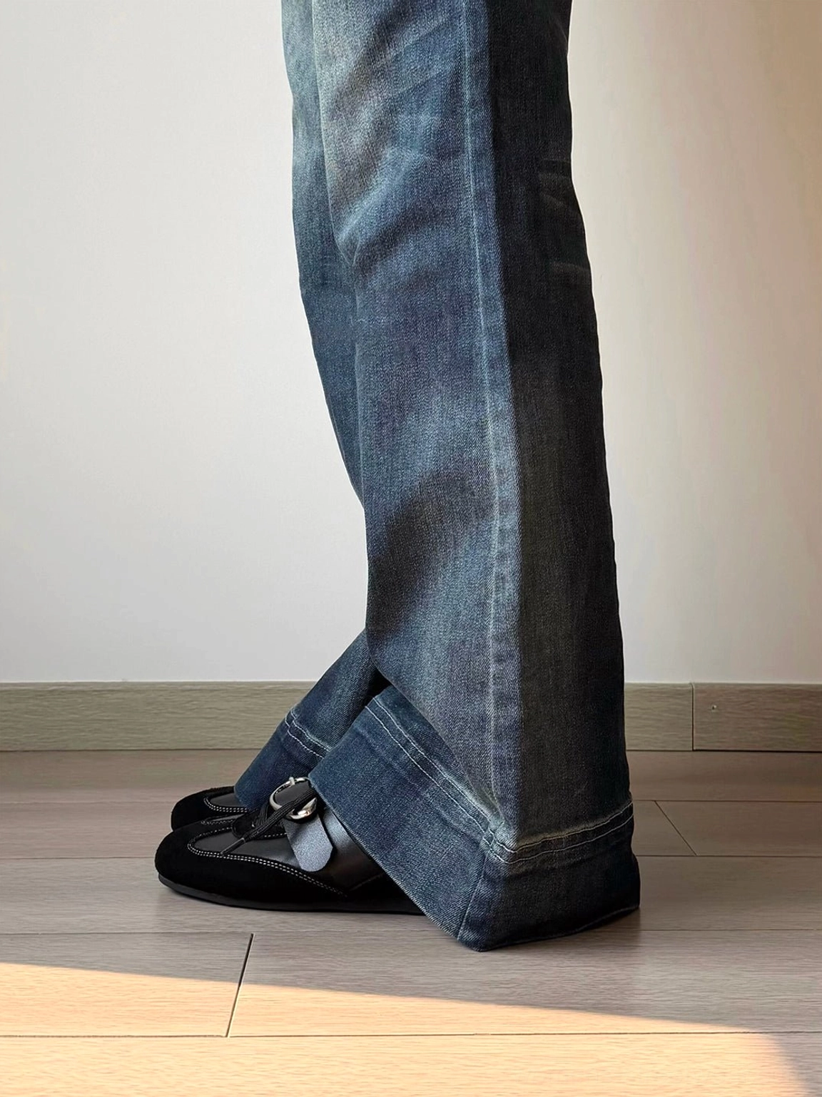 Black leather German trainer sneaker styled under wide-leg blue denim jeans with metallic vamp accent