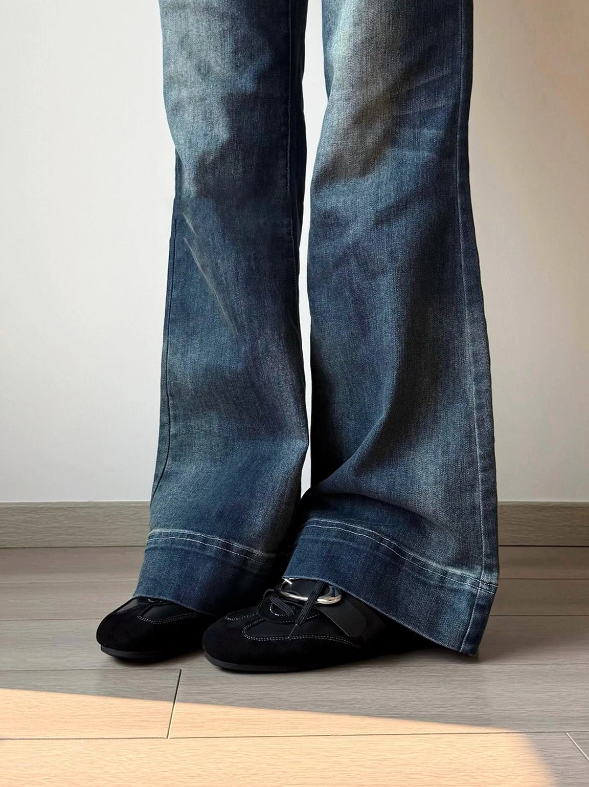Pair of black leather German trainer sneakers worn with wide-leg blue jeans in a modern streetwear look