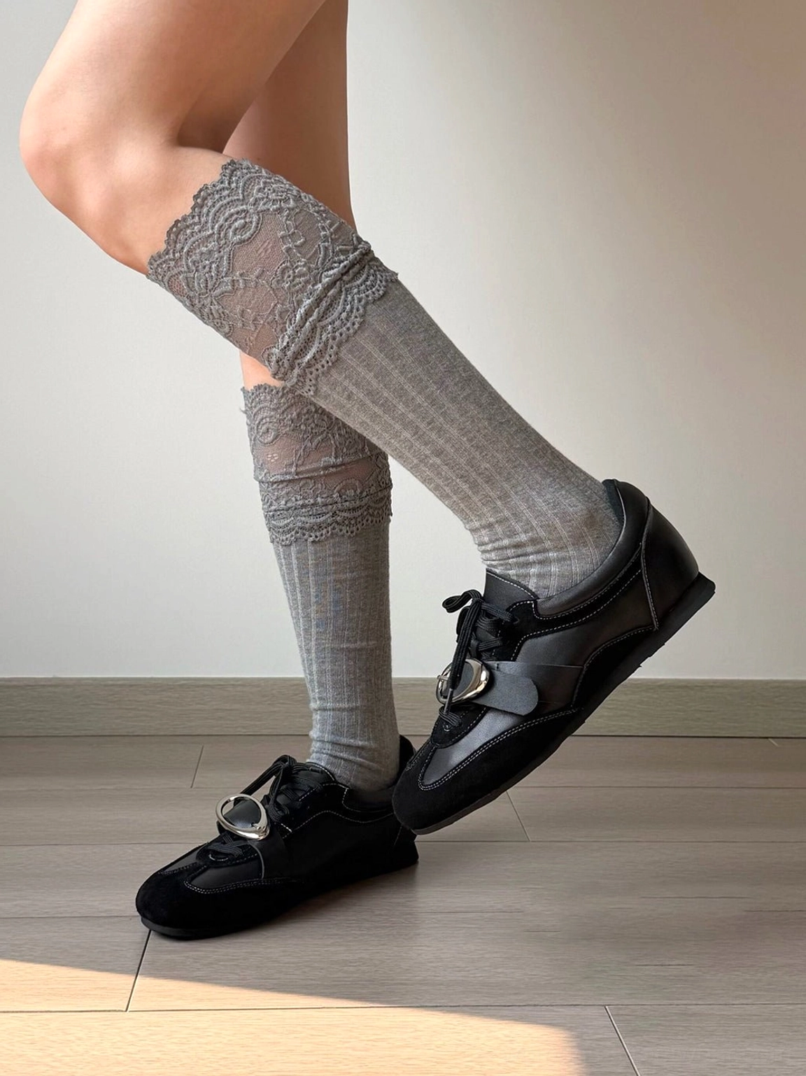 Black leather German trainer sneaker worn with grey lace-trimmed knee-high socks showing metallic vamp detail