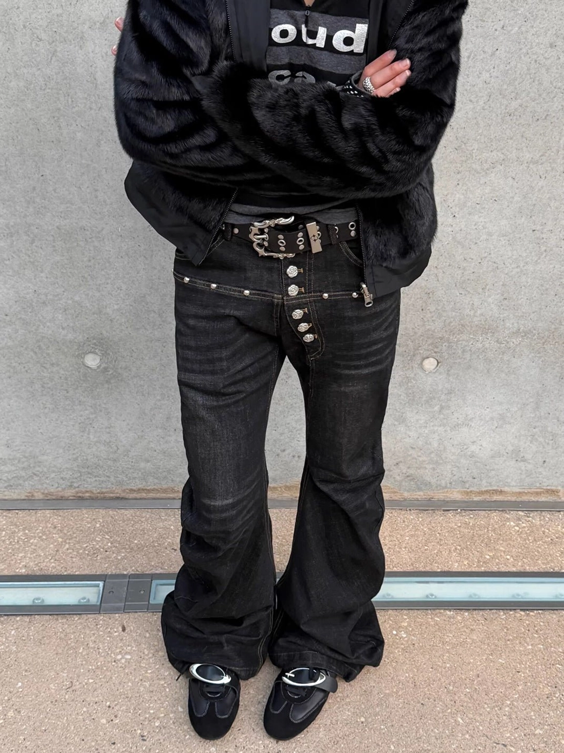 Black leather German trainer sneakers paired with flared denim and a dark contemporary streetwear outfit