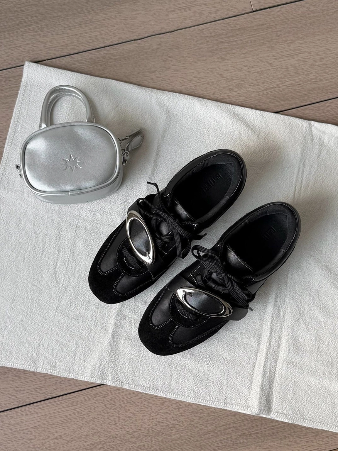 Black leather low-top German trainer sneakers with folded tongue and fashion-forward metallic accent