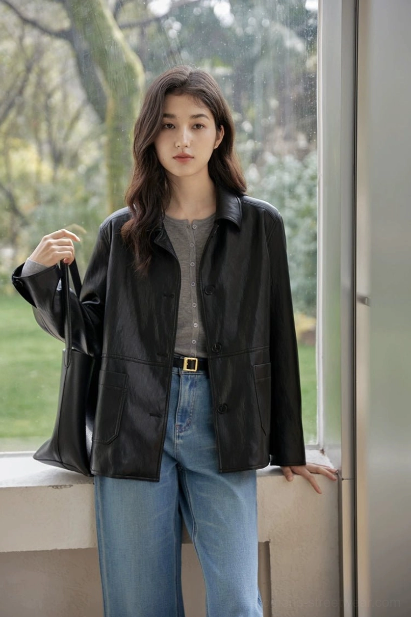 Close-up three-quarter view of a women’s black leather jacket with shirt collar and practical side pockets