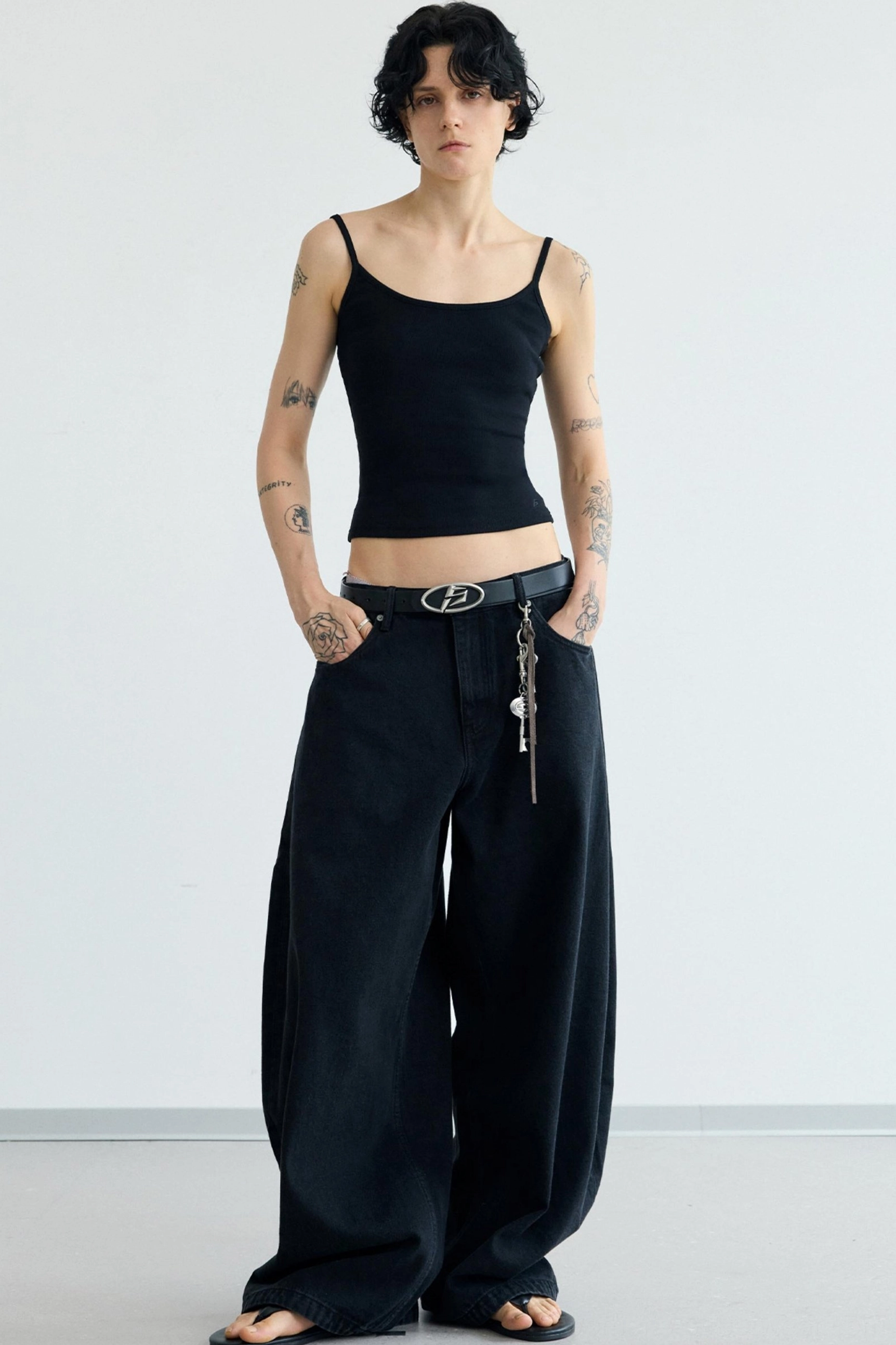 Front view of women's black minimalist cropped camisole tank top with slim silhouette and spaghetti straps