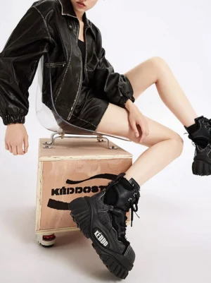 Black women's platform combat boots styled with leather streetwear clothing, showing the chunky sculpted outsole and elevated punk work boot profile