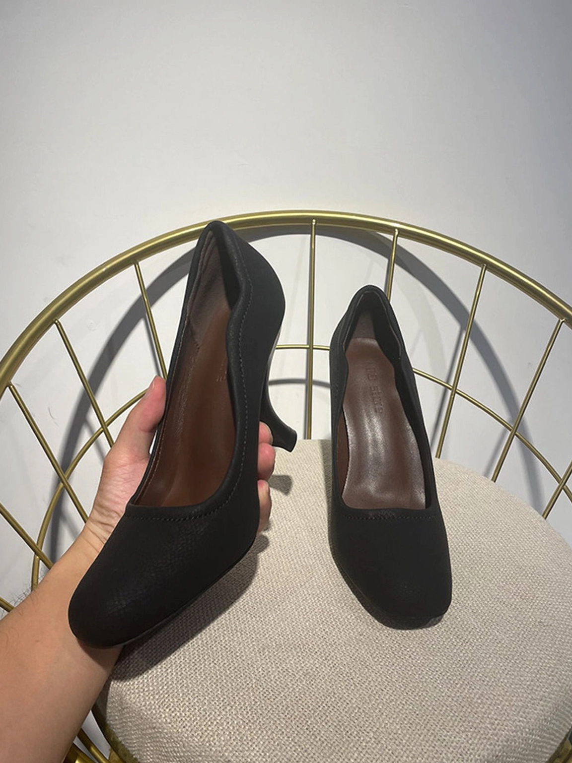 Black round-toe sculpted heel pump in side three-quarter view showcasing its curved architectural heel and matte finish