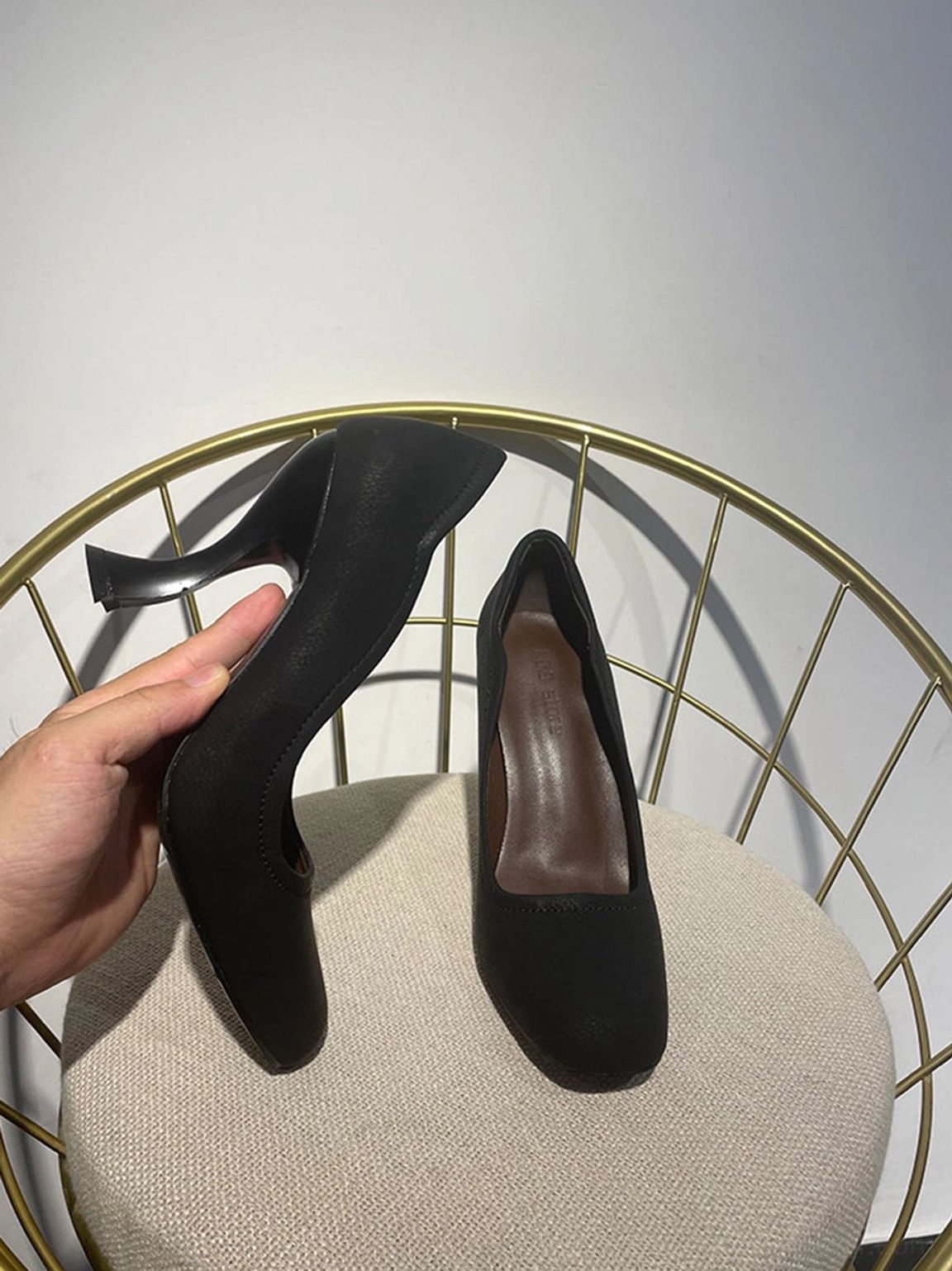 Side view of black women's sculpted heel pump highlighting the dramatic curved high heel and smooth matte upper
