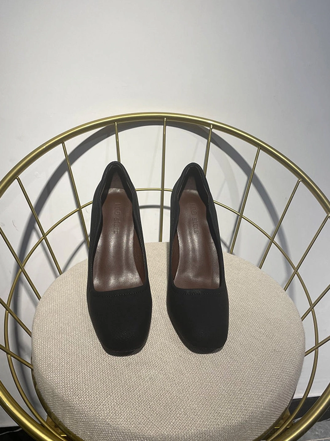 Pair of black round-toe sculpted heel pumps in top view with visible brown insoles and asymmetric openings