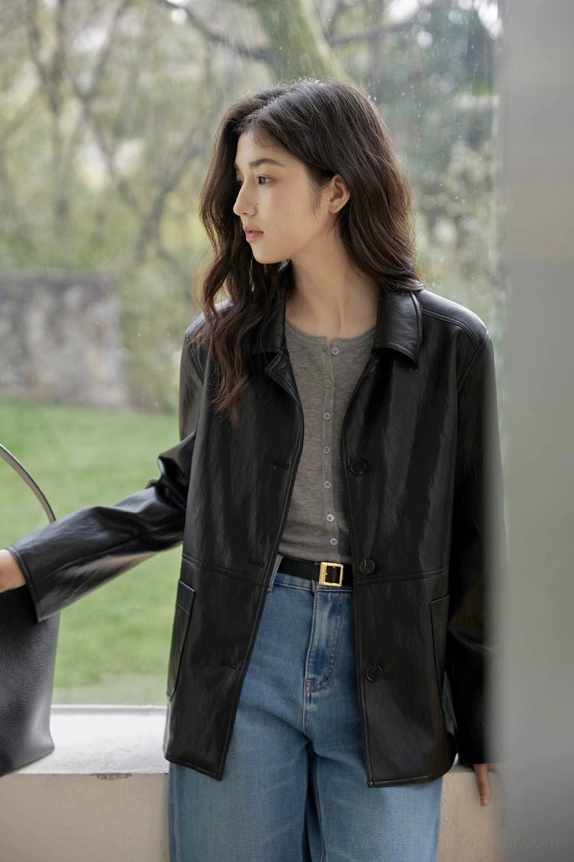 Close side view of a women’s black short leather jacket showing front flap pockets and soft leather texture