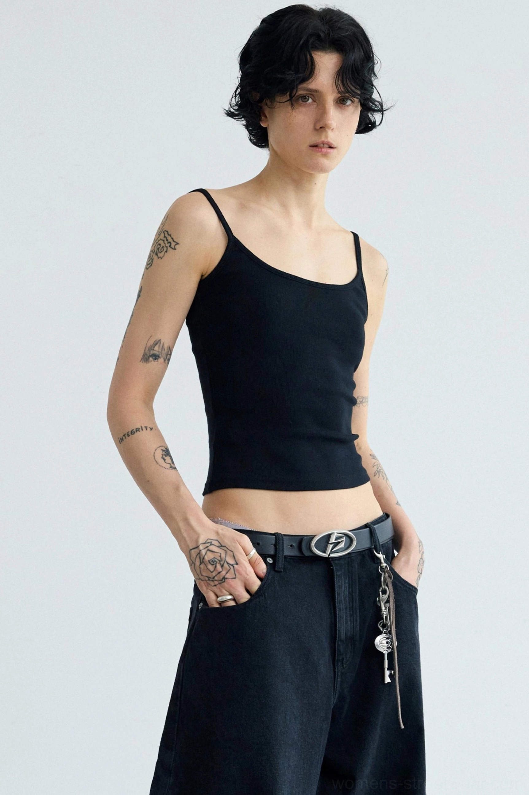 Three-quarter view of women's black slim fit cropped camisole tank top with spaghetti straps and streetwear jeans