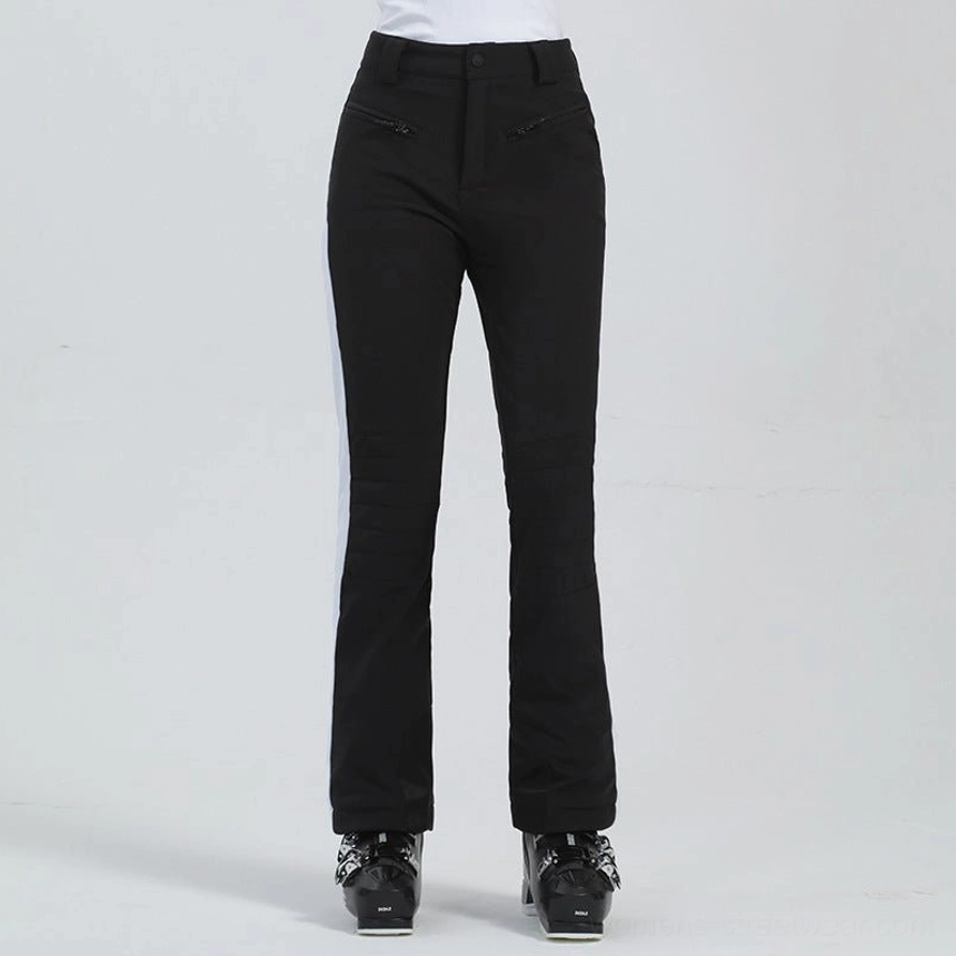 Black women's streetwear ski pants with white contrast side panel, zippered pockets, tailored flare, and ski boot fit