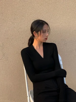 Side view of a black fitted V-neck ribbed knit top with long sleeves and minimalist streetwear styling
