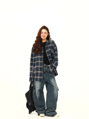 Back three-quarter view of a woman wearing a relaxed blue plaid oversized flannel shirt with wide-leg jeans and casual sneakers