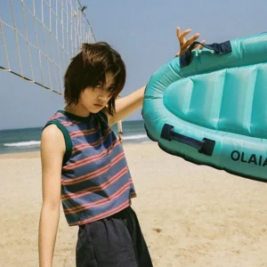 Blue striped cropped tank top with contrast trim worn by a woman beside a beach volleyball net