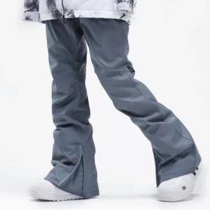 Bluish gray women's flared ski pants with three-dimensional seams, boot-friendly hem zipper, white snow boots, and tie-dye ski jacket