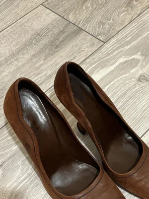 Top view of brown sculpted heel round-toe pumps with dark brown insoles and matte leather-look uppers
