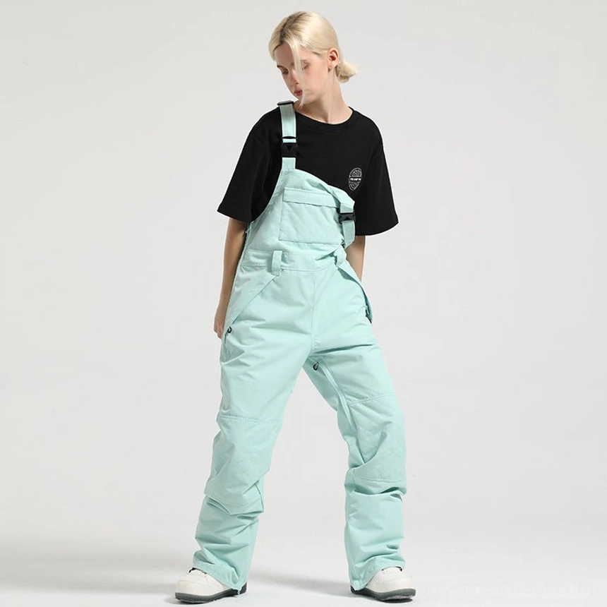 Mint green women's bib snow overalls with loose fit, zippered side pockets, and gorpcore winter styling