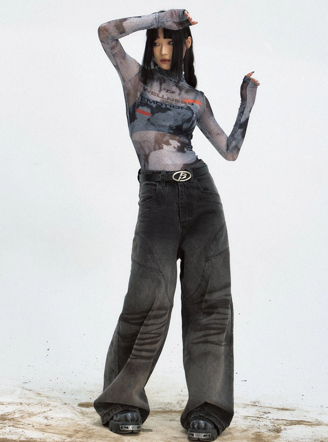 Women's cropped black sheer mesh graphic top with high neckline and long sleeves styled with washed black streetwear jeans