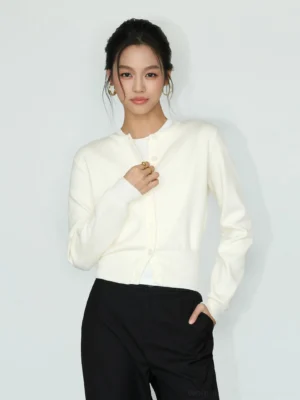 Light apricot women's cropped crew neck button front knit cardigan in a three-quarter front studio view