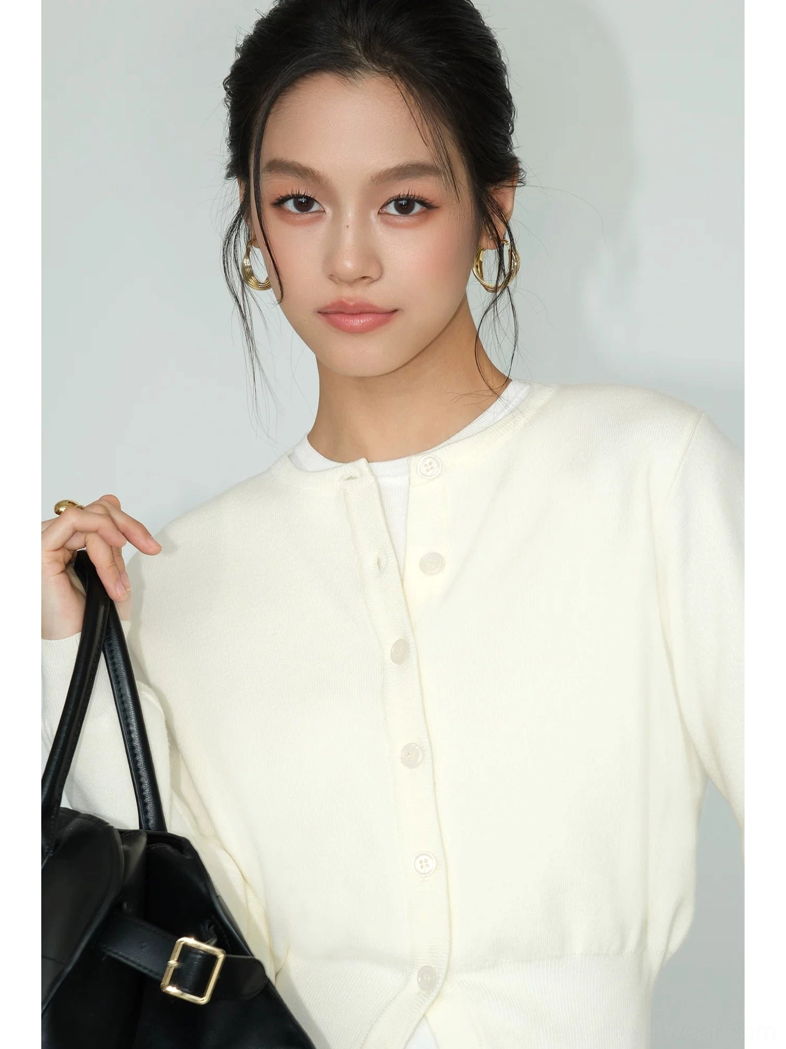 Close-up of light apricot cropped crew neck knit cardigan showing front buttons ribbed cuffs and hem