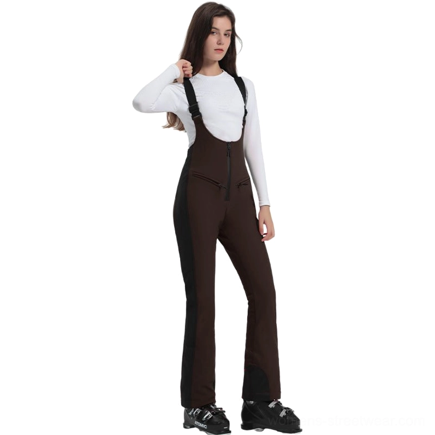Women's dark brown bib ski overalls with black side panels, front center zipper, flared pant legs, black hem trim, and ski boots