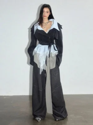 Women's dark gray asymmetric lace trim hybrid cropped blazer styled with wide leg black denim in a minimalist studio front view