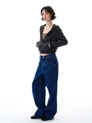 Women's dark gray cropped zip-up streetwear hoodie shown in three-quarter view with wide-leg denim jeans